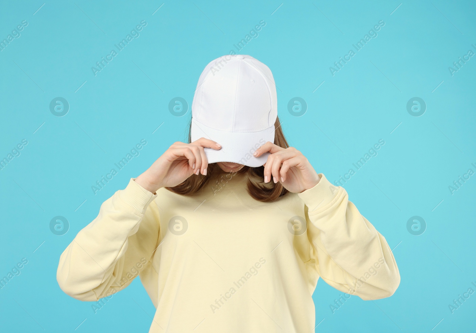 Photo of Young woman wearing stylish white baseball hat on light blue background
