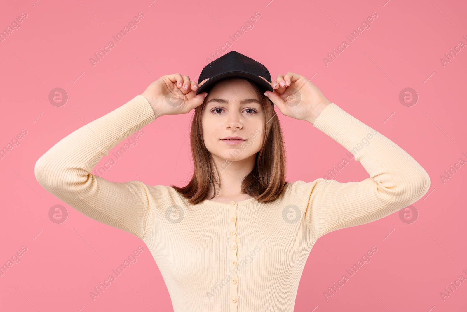 Photo of Young woman wearing stylish black baseball hat on pink background