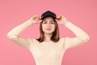 Photo of Young woman wearing stylish black baseball hat on pink background
