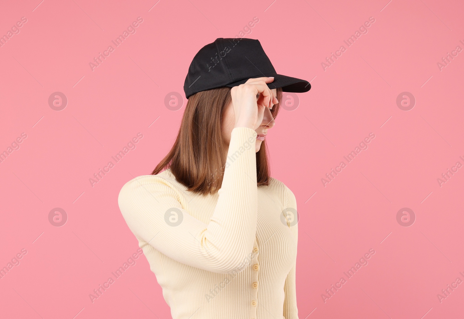 Photo of Young woman wearing stylish black baseball hat on pink background