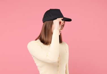 Photo of Young woman wearing stylish black baseball hat on pink background