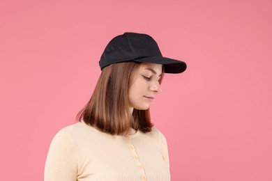 Photo of Young woman wearing stylish black baseball hat on pink background