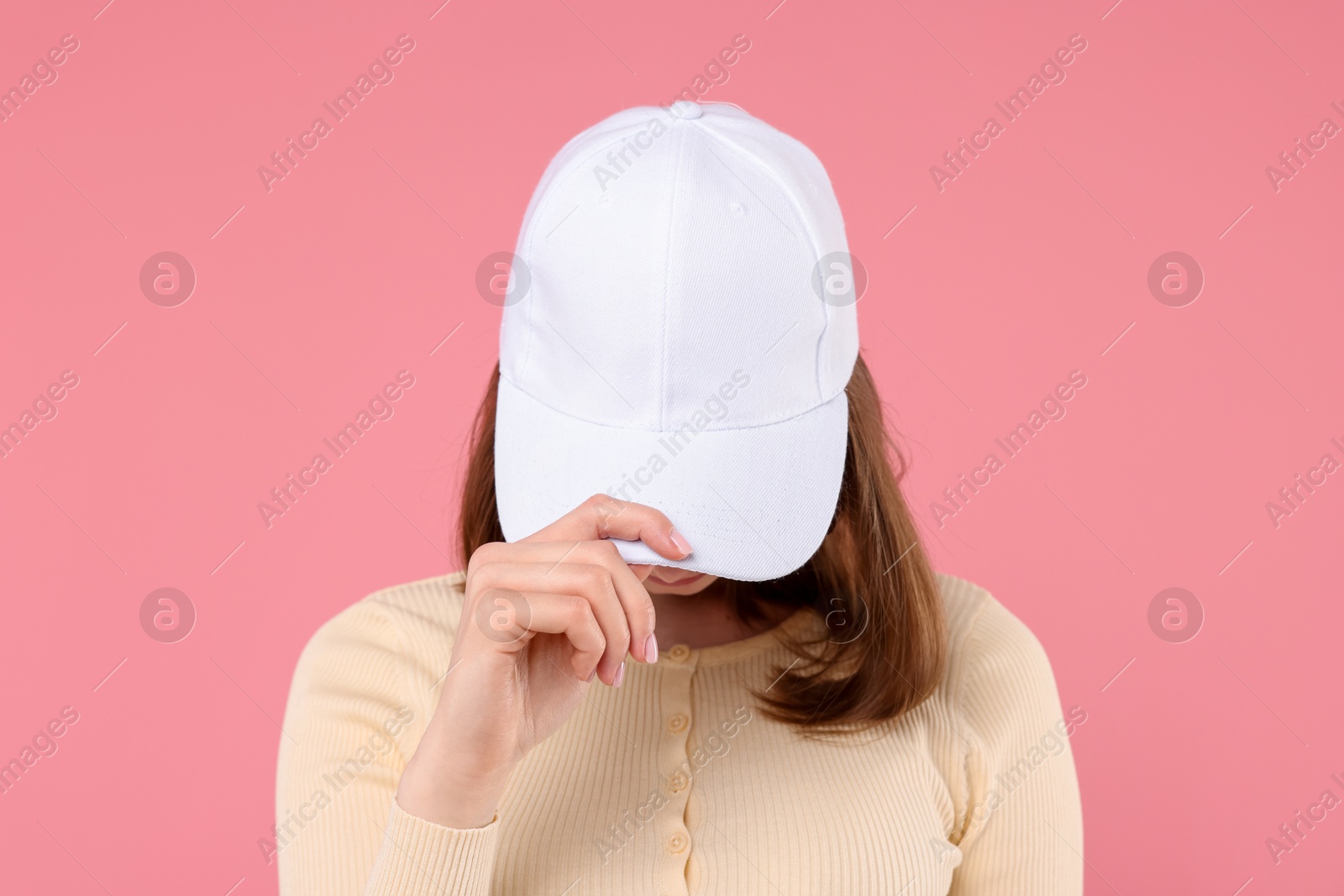 Photo of Young woman wearing stylish white baseball hat on pink background