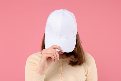 Photo of Young woman wearing stylish white baseball hat on pink background