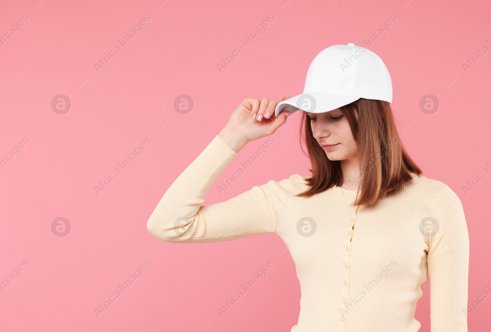 Photo of Young woman wearing stylish white baseball hat on pink background, space for text