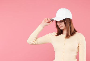 Photo of Young woman wearing stylish white baseball hat on pink background, space for text