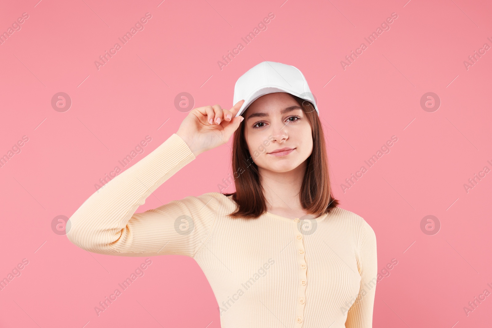 Photo of Young woman wearing stylish white baseball hat on pink background