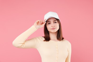 Photo of Young woman wearing stylish white baseball hat on pink background