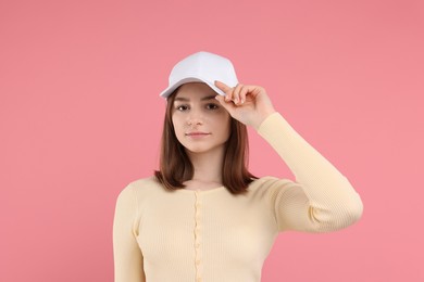 Photo of Young woman wearing stylish white baseball hat on pink background
