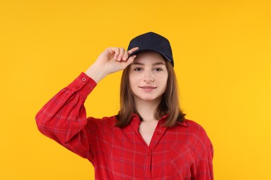 Photo of Young woman wearing stylish black baseball hat on yellow background