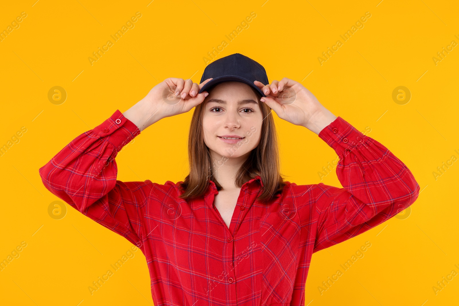 Photo of Young woman wearing stylish black baseball hat on yellow background