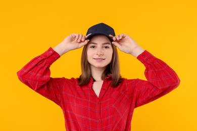 Photo of Young woman wearing stylish black baseball hat on yellow background