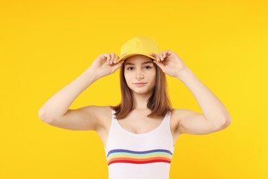Photo of Young woman wearing stylish baseball hat on yellow background