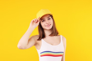 Photo of Young woman wearing stylish baseball hat on yellow background