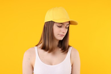 Photo of Young woman wearing stylish baseball hat on yellow background