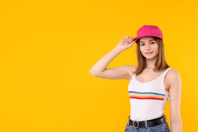 Photo of Young woman wearing stylish pink baseball hat on yellow background, space for text