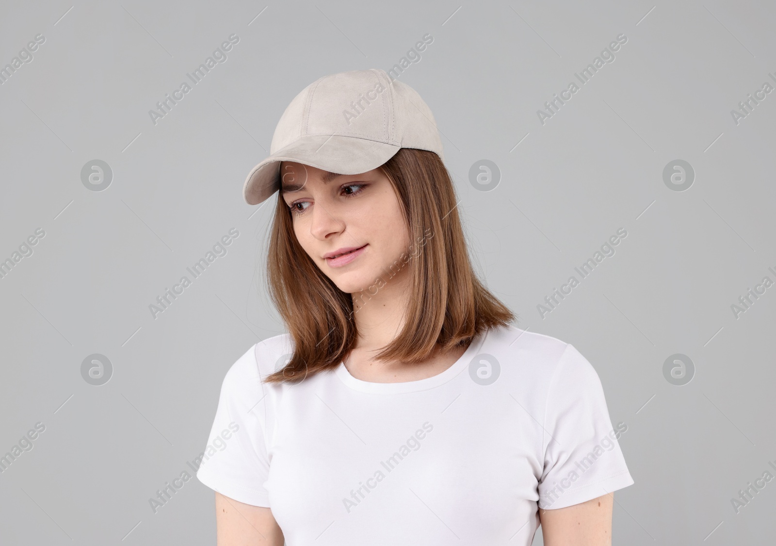 Photo of Young woman wearing stylish beige baseball hat on light grey background