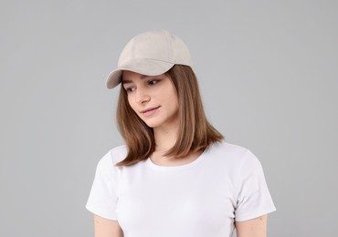 Photo of Young woman wearing stylish beige baseball hat on light grey background