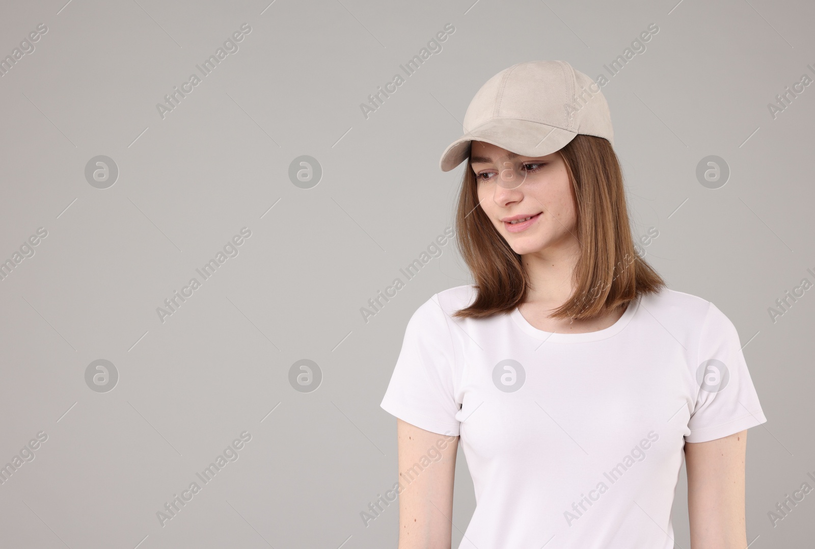 Photo of Young woman wearing stylish beige baseball hat on light grey background, space for text