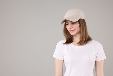 Photo of Young woman wearing stylish beige baseball hat on light grey background, space for text