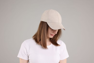 Photo of Young woman wearing stylish beige baseball hat on light grey background