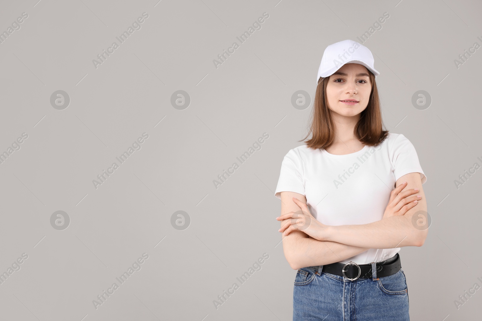 Photo of Young woman wearing stylish white baseball hat on light grey background, space for text