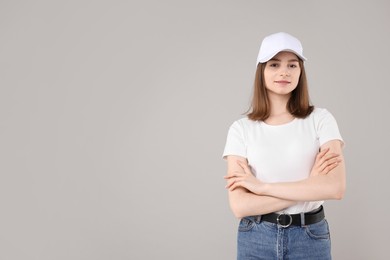 Photo of Young woman wearing stylish white baseball hat on light grey background, space for text