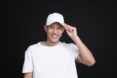 Photo of Young man wearing stylish white baseball hat on black background