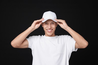 Photo of Young man wearing stylish white baseball hat on black background