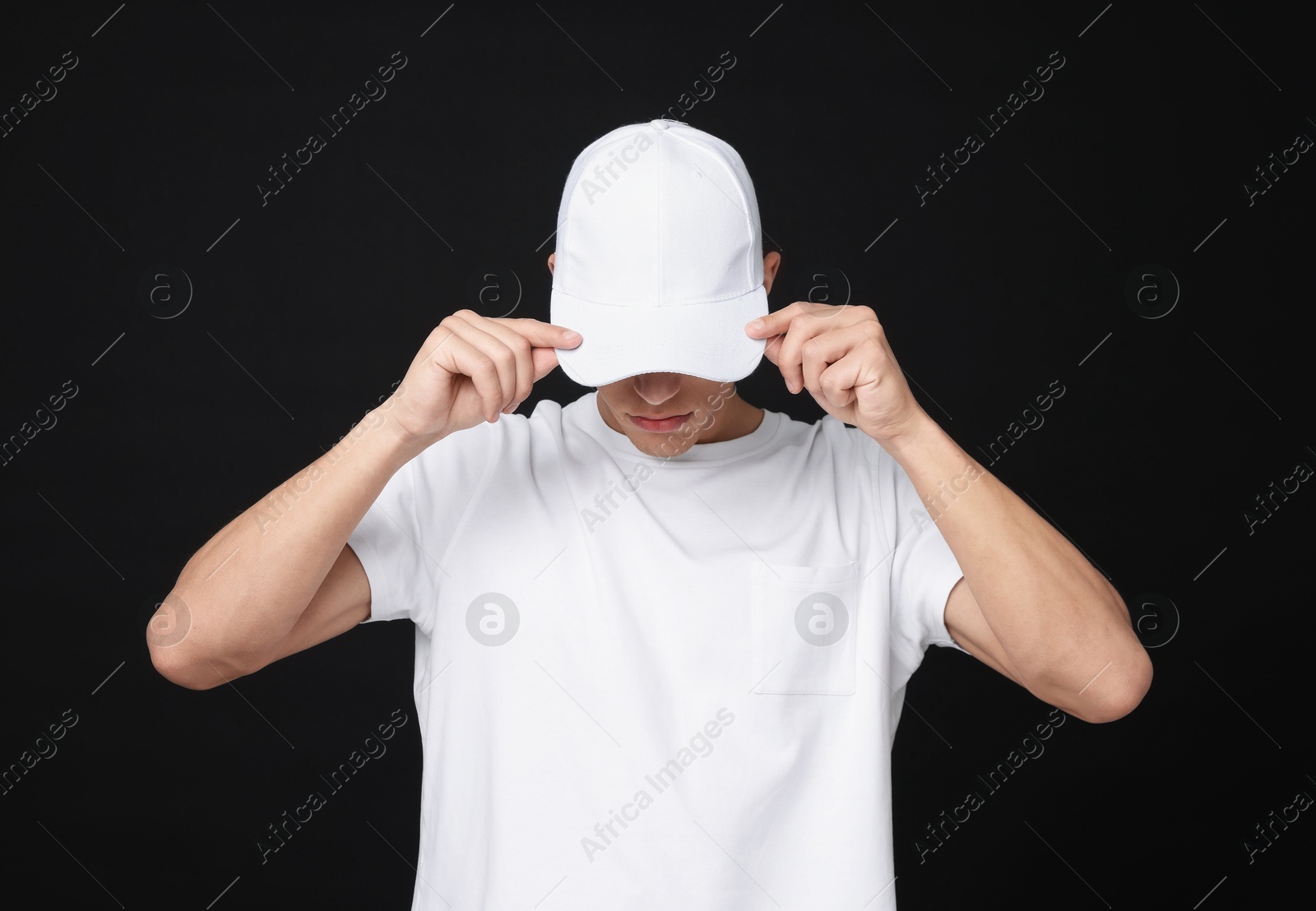Photo of Young man wearing stylish white baseball hat on black background
