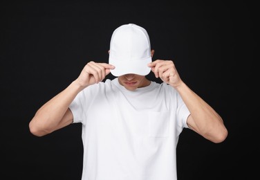 Photo of Young man wearing stylish white baseball hat on black background