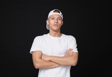 Photo of Young man wearing stylish white baseball hat on black background