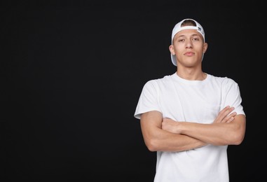 Photo of Young man wearing stylish white baseball hat on black background, space for text