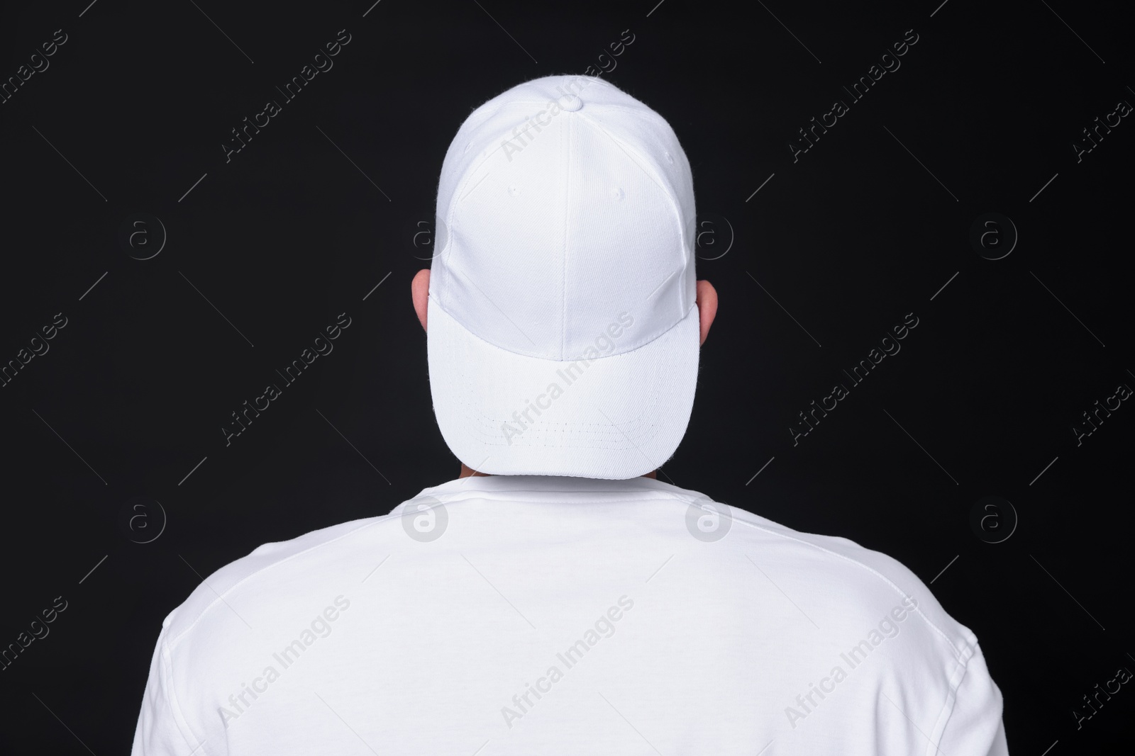 Photo of Young man wearing stylish white baseball hat on black background, back view