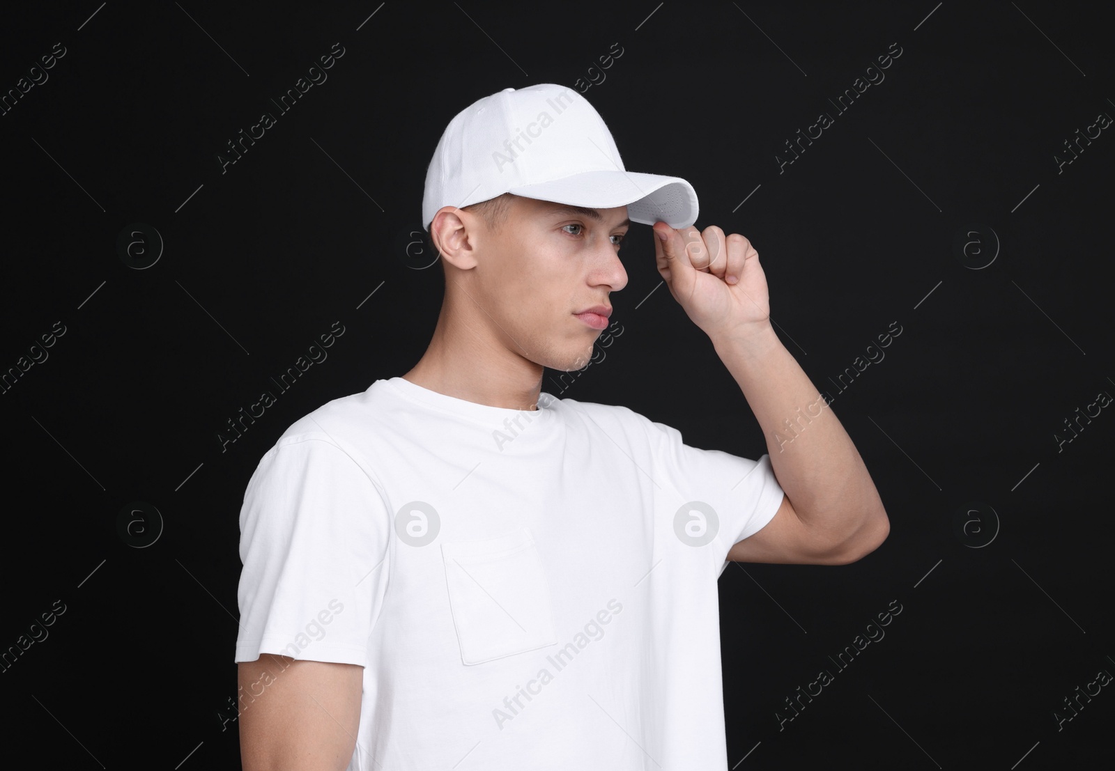 Photo of Young man wearing stylish white baseball hat on black background
