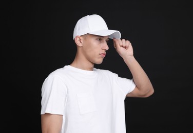 Photo of Young man wearing stylish white baseball hat on black background