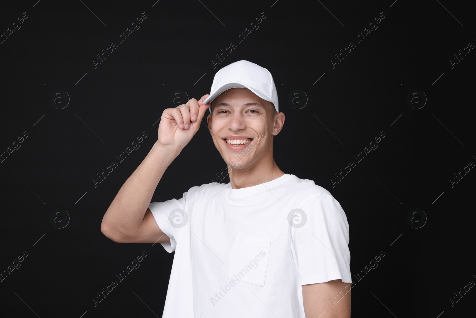 Photo of Young man wearing stylish white baseball hat on black background