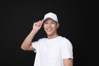 Photo of Young man wearing stylish white baseball hat on black background