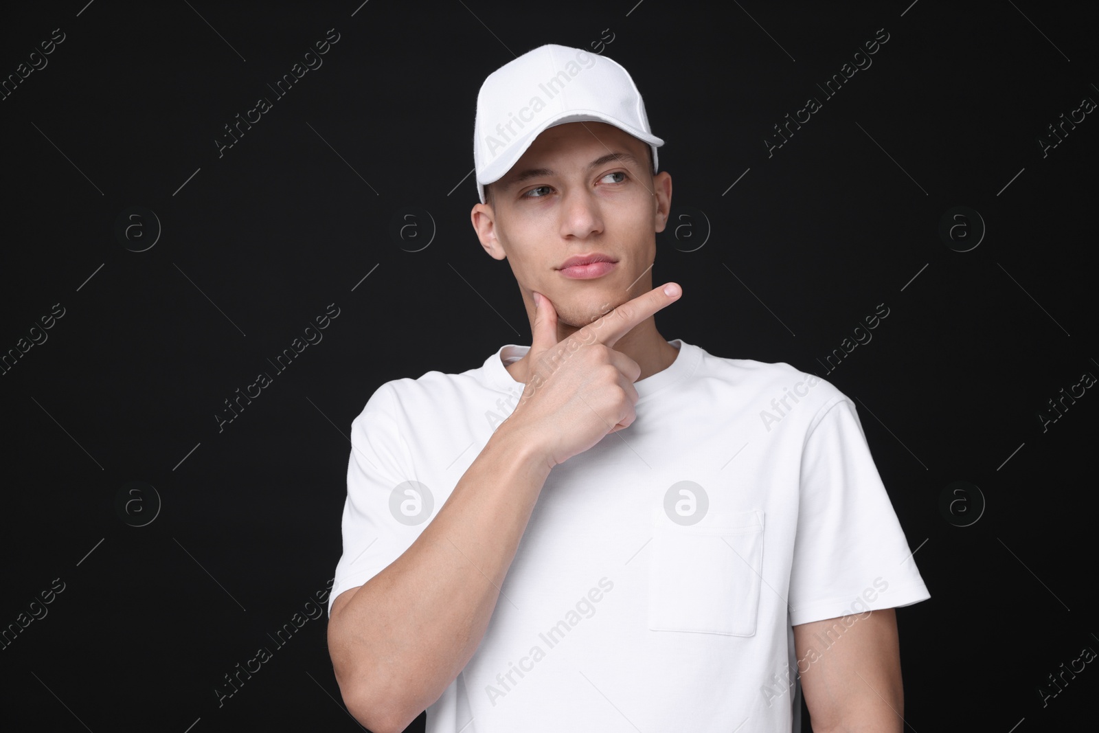 Photo of Young man wearing stylish white baseball hat on black background