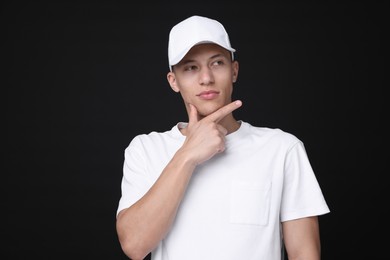 Photo of Young man wearing stylish white baseball hat on black background