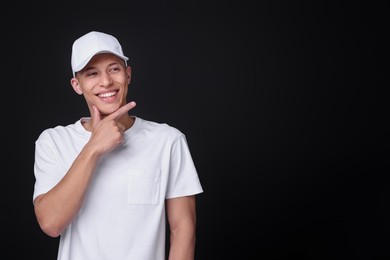 Photo of Young man wearing stylish white baseball hat on black background, space for text