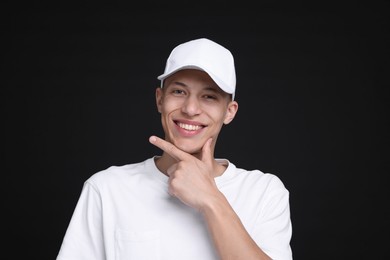 Photo of Young man wearing stylish white baseball hat on black background