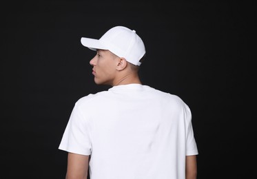 Photo of Young man wearing stylish white baseball hat on black background