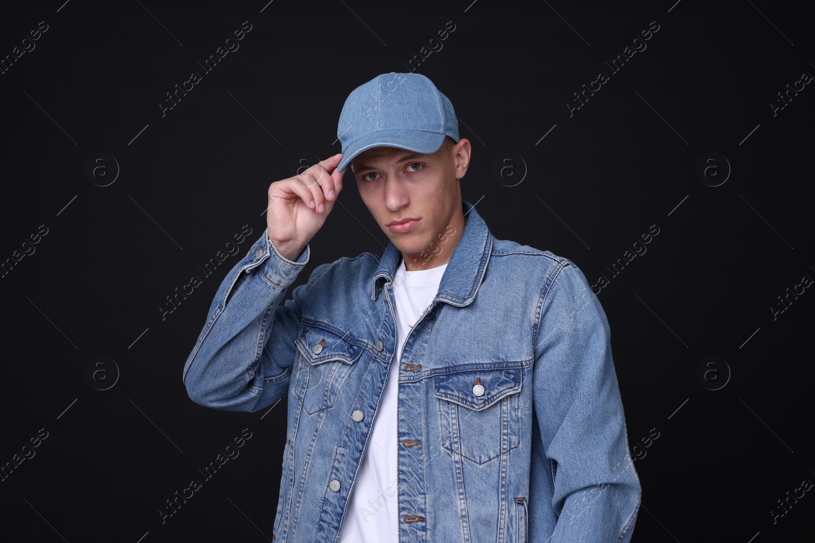 Photo of Young man wearing stylish denim baseball hat on black background