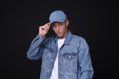 Photo of Young man wearing stylish denim baseball hat on black background