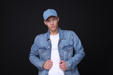 Photo of Young man wearing stylish denim baseball hat on black background
