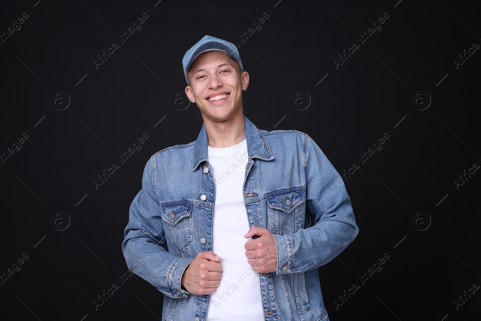 Photo of Young man wearing stylish denim baseball hat on black background