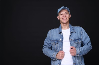 Photo of Young man wearing stylish denim baseball hat on black background, space for text