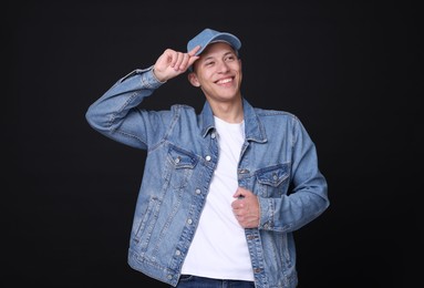 Photo of Young man wearing stylish denim baseball hat on black background