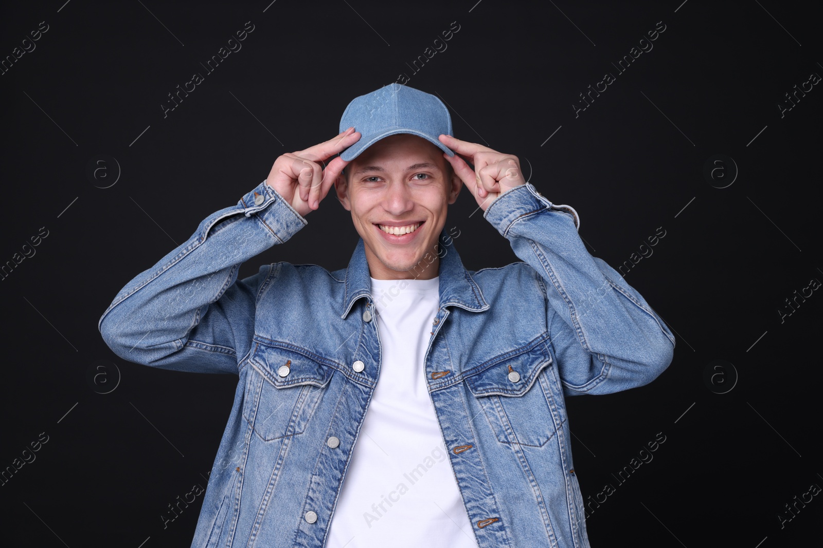 Photo of Young man wearing stylish denim baseball hat on black background